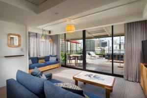 a living room with a blue couch and a table at The Surfjack Hotel & Swim Club in Honolulu
