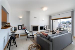 een woonkamer met een grijze bank en stoelen bij Casa Kiki in Ferragudo