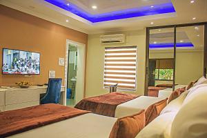 um quarto de hotel com três camas e uma televisão em New Fairmount Hotel and Casino em Livingstone