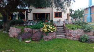 ein Haus mit einer Steinmauer und Blumen im Hof in der Unterkunft La Casona de Gise in La Adela