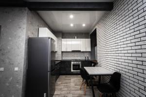 a kitchen with a refrigerator and a table with chairs at Loft Apartment on Svobody in Kamianske