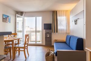 uma sala de estar com um sofá azul e uma mesa em Résidence Pierre & Vacances La Baie des Sables em Les Sables-dʼOlonne