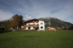 a house in a field with mountains in the background at Landhaus Loipe in Leutasch