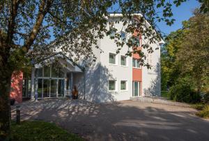 a white building with a tree in front of it at Bergers Airporthotel Memmingen in Memmingerberg