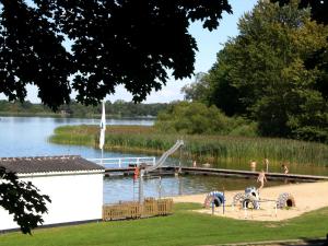 - une aire de jeux sur la rive d'un lac avec des personnes sur un quai dans l'établissement Landhaus am Schaalsee, à Zarrentin