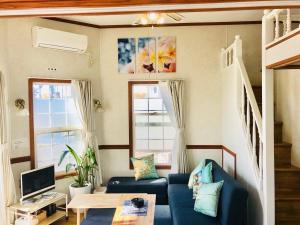 a living room with a blue couch and two windows at Mini Chula Inn in Chatan