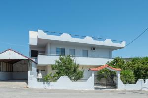 a white house with a white fence in front of it at Paulsia Apartments in Psinthos