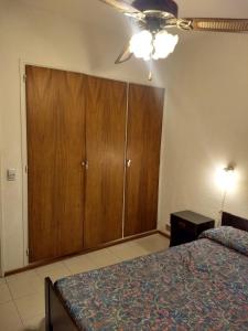 1 dormitorio con 1 cama y armario de madera en Playa Club Argentina en Miramar