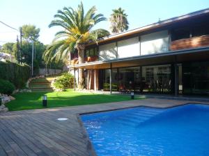 una casa con piscina frente a ella en VILLA DEL BOSQUE, en Castelldefels