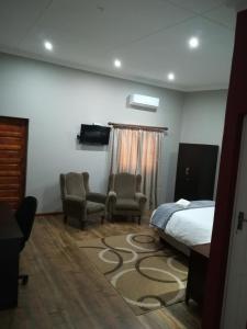 ein Schlafzimmer mit 2 Stühlen, einem Bett und einem Teppich in der Unterkunft Tranquil House B&B @ 121 Berry St in Queenstown