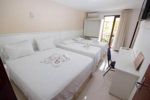 1 dormitorio con 2 camas con sábanas blancas en Pousada dos Jangadeiros, en Maragogi