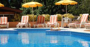 a group of chairs and umbrellas next to a swimming pool at Complejo Viva Zapata in Mar de las Pampas