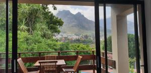 a balcony with a table and chairs and a mountain at The Salt House Guest House in Hout Bay in Hout Bay
