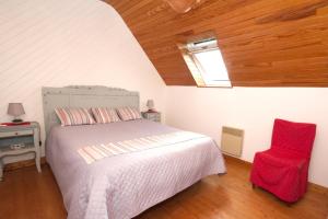 a bedroom with a bed and a red chair at La Maison aux Volets Bleus de Prat An Ilis à 900m de la plage du Guilvinec in Le Guilvinec