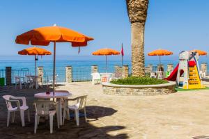 tavolo e sedie con ombrelloni arancioni e parco giochi di Acciaroli Vacanze Residence ad Acciaroli