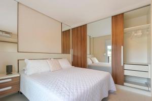 1 dormitorio con cama blanca y espejo en Centro de Canela Apartamento Lindo, en Canela