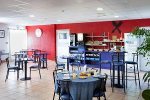 a restaurant with tables and chairs and a kitchen at Audotel in Carcassonne +41 photos