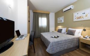 a hotel room with a bed and a desk with a computer at Matiz Jaguariúna in Jaguariúna