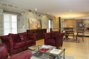 a living room with red furniture and a stone wall at Casa da Ponte do Porto in Amares