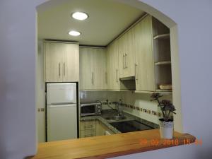 eine Küche mit Holzschränken und einem weißen Kühlschrank in der Unterkunft 29 Calle Cártama in La Cala de Mijas + 5 Fotos