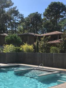 a swimming pool in a backyard with a fence at Domaine du Ferret Restaurant & Spa in Cap-Ferret