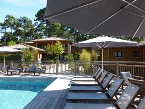 a pool with chairs and umbrellas next to a house at Domaine du Ferret Restaurant & Spa in Cap-Ferret