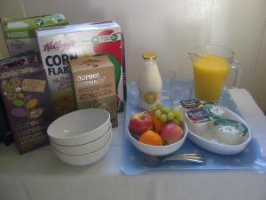 ein Frühstückstablett mit einer Schachtel Müsli-Obst und einem Glas Saft in der Unterkunft Bijou B&B Lulworth in Lulworth Cove