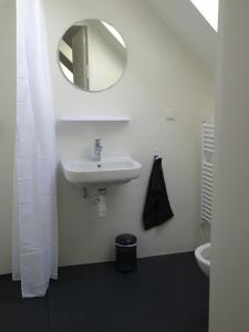 a white bathroom with a sink and a mirror at Het Bakkersschuurtje in Colijnsplaat