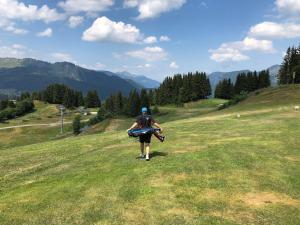 a man walking down a grassy hill with a surfboard at ORTA Chalet in Les Gets