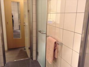 a bathroom with a shower with a towel and a mirror at Furano Hotel in Furano