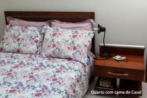 a bed with a floral bedspread and pillows next to a desk at casa duplex in Vitória