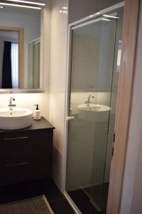 baño con lavabo y puerta de ducha acristalada en Buborék apartman, en Tata