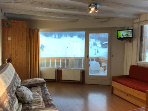 a living room with a couch and a large window at Studio pied de pistes balcon et vue montagne in Montgenèvre