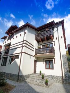 Biały dom z balkonami i schodami w obiekcie Chez Marcel Sinaia w mieście Sinaia