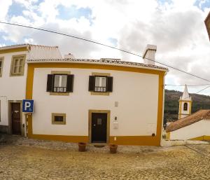 a white and yellow house with a blue door at Casa da Avó Tina in Castelo de Vide