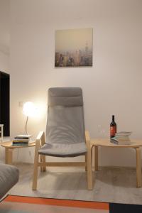 een stoel in een woonkamer met een tafel en een lamp bij Cozy Apartments - City Center in Iaşi