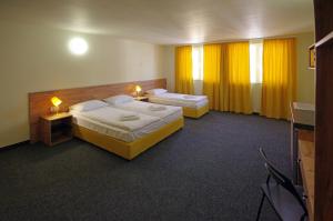 2 Betten in einem Hotelzimmer mit gelben Vorhängen in der Unterkunft Стаи за Гости "ЦЕНТРАЛ" Фамилни Стаи & Апартаменти in Gabrowo