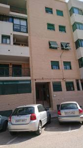 two cars parked in a parking lot in front of a building at Habitación individual con baño privado, Desayuno y piscina in Alboraya