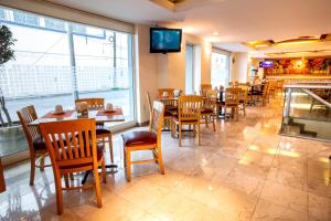 Hotel Plaza Calzada في مونتيري: مطعم به طاولات وكراسي وتلفزيون على الحائط
