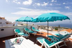 patio z niebieskimi krzesłami i parasolami na dachu w obiekcie "ATIS" w mieście Puerto de Santiago