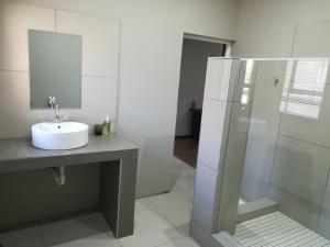 een witte badkamer met een wastafel en een douche bij Tranquil House B&B @ 121 Berry St in Queenstown