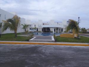 a building with a pool and palm trees next to a street at Casa de vacaciones in Veracruz
