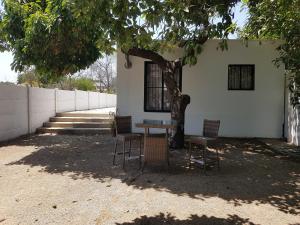 einen Tisch und Stühle unter einem Baum neben einem Gebäude in der Unterkunft Apartamento La Calera in La Calera