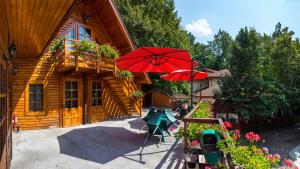 a wooden cabin with a red umbrella in front of it at Pensiunea Casa Verde Bucuresti in Bucharest