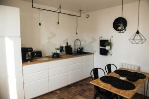 a kitchen with white cabinets and a table at -LA CORDIALITÉ- in Ault