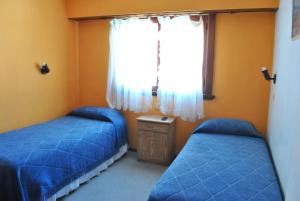 1 dormitorio con 2 camas azules y ventana en Hotel Bamba en Villa Gesell