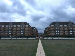 two large buildings in a grassy field next to a building at The golden triangle Apartment in Deauville +3 photos