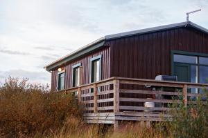 a wooden house with windows on top of a field at Hestaland Riverside Cottage in Staðarhús