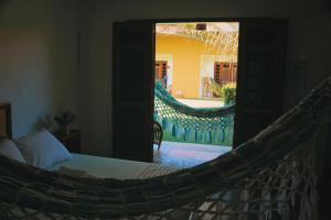 a hammock in a bedroom with a view of a backyard at Pouso do Kite Pousada Flecheiras in Flecheiras