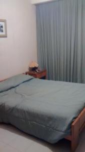 een slaapkamer met een bed en een raam met gordijnen bij Playa Club Argentina in Miramar
